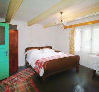 Rustic bedroom in a family house with green doors and wooden beams on the ceiling.