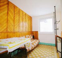 Interior of a family house with wooden paneling, a sofa, and a table with a tablecloth.