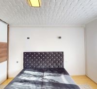 Bedroom in a 2-room apartment with an upholstered bed headboard and wardrobes with a wooden decor.