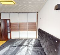 Bedroom in a 2-room apartment with a large wardrobe and a bed, floor with wood decor.