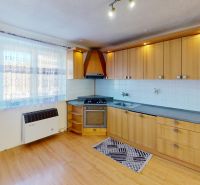 A kitchen in a 2-room apartment with a wood-patterned floor and light furnishings.