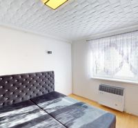 A bright bedroom in a two-room apartment with an upholstered headboard and a wooden decor floor.