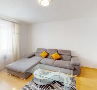 Living room with a sofa and a glass table in a two-room apartment with a wooden decor floor.