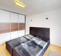 A bright bedroom with a large bed, built-in wardrobe, and wood-decor flooring in a 2-room apartment.