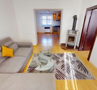 Living room in a two-room apartment with a sofa, tiles, and a wooden decor floor.