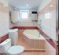 Bathroom in a 2-room apartment with a bathtub, washing machine, and tiled walls.