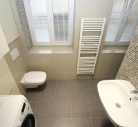 Bathroom in a 2-room apartment with a washing machine, shower, and window with blinds.