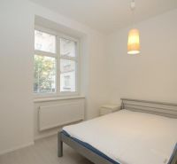 Bedroom in a 2-room apartment with a simple bed and a pendant light.