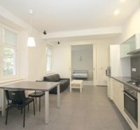 A kitchen with a dining area and a view into the bedroom in a 2-room apartment.
