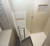 A bathroom with a shower and light tiles in a 2-room apartment.