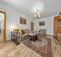 Living room with wood-patterned flooring, sofa, and carpet in a 3-room apartment.