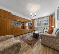 Living room in a 3-room apartment with older furniture and a wooden decor floor.