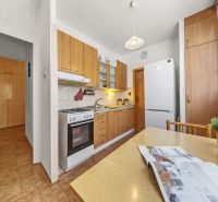 A kitchen in a 3-room apartment with a wooden decor floor and light furniture.