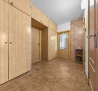 A hallway with built-in wardrobes, tiles, and a brick wall in a 3-room apartment.