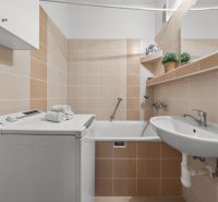 Bathroom with a washing machine in a 3-room apartment, beige tiles, sink, bathtub, shelves.