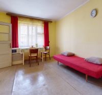Yellow walls, a bed with a red throw, two chairs, a table in a family house.