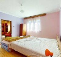 Bedroom in a family house with a wooden decor floor, pastel walls, bed.