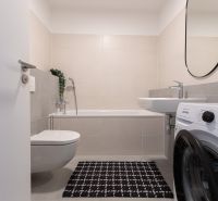 Bathroom in a 2-room apartment with a bathtub, washing machine, and toilet.