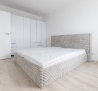 Bedroom in a two-room apartment with wood-patterned flooring, built-in wardrobe, and bed.