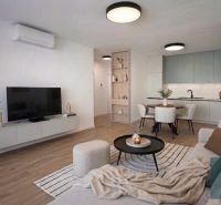 Living room with kitchen, wood-decorated flooring, light furniture, and a dining table.
