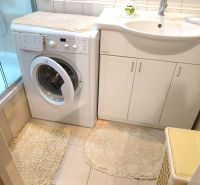 Bathroom with a shower, washing machine, and sink, ideal for a 3-room apartment.