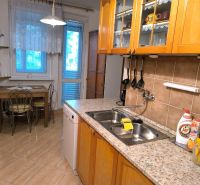 A kitchen in a 3-room apartment with a wooden decor floor and a dining table.
