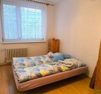 A bedroom with a bed and a wooden decor floor in a 3-room apartment.