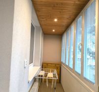 Glazed balcony with a wooden ceiling and a clothes dryer in a 3-room apartment.
