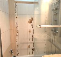 A bathroom with a shower and floral tiles in a 3-room apartment.