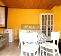 Interior of a garden with a white dresser, table, and wicker furniture, yellow walls.