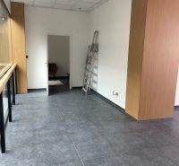 Interior of commercial spaces with dark tiles and simple walls, white ceiling structure.