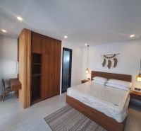 Bedroom of the villa with wood-patterned flooring, a wardrobe, and wall decoration.
