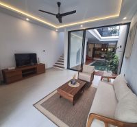 Living room in a villa with wood-patterned flooring, view of the pool.