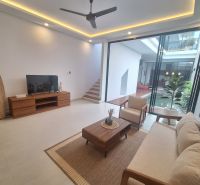 A bright living room of a villa with comfortable furniture and glass doors to the terrace.