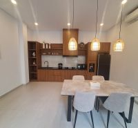 Dining area in a villa with a kitchen unit and pendant lamps.