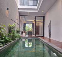 Villa in Bali with a pool and plants, terrace with wooden decor flooring.