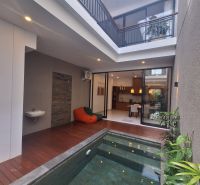 Interior of a villa with a pool, wooden floor decor, and comfortable seating.