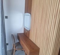 A wooden table with a chair and wooden wall decor in a villa room.