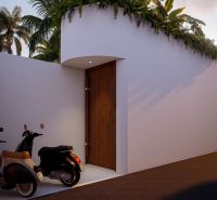 Entrance to the villa in Bali with motorcycles and vegetation on the wall.