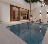 A pool in a villa in Bali with loungers and a staircase.
