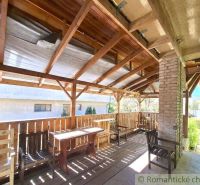 Covered terrace of a family house in Lupoč with wooden seating and a view of the garden.