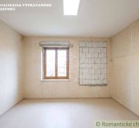 A room with wallpaper and a window in a family house, floor with wooden decor.