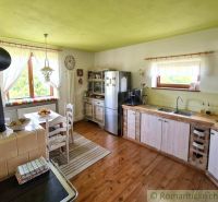 Rustic kitchen in a family house with a wood-patterned floor and a traditional stove.