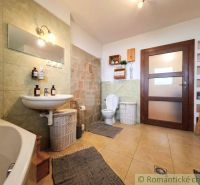 A bathroom in a family house with light tiles, a sink, and a bathtub.