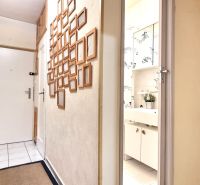 A hallway with a wall full of empty frames in a studio apartment.