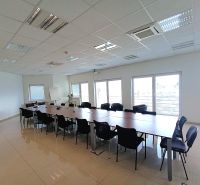 Spacious offices with a long table and many chairs, tiled floor.