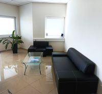 Leather sofa and glass table in an office with tiled flooring.