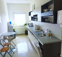 The kitchen in the offices with white walls, a sink, and a table with chairs.