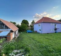 A family house in Kosihovce with a colorful facade, a large yard, and an adjacent farm building.