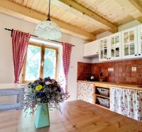 A kitchen in a cottage with a wooden ceiling, a floor with a wooden decor, flowers on the table.